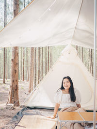 Happy asian teenage girl in front of camp tent. outdoor activity. 