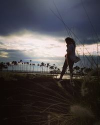 Side view of woman walking on shore during sunset