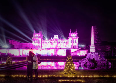 Rear view of people standing at night