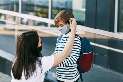 Mother adjusts her son's mask. a mother and child on their way to school or kindergarten during 