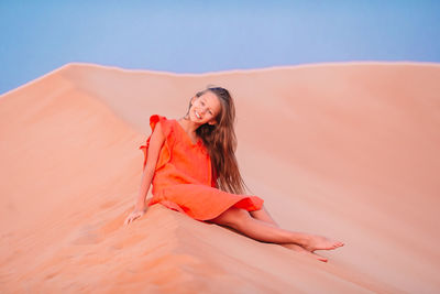 Portrait of young woman against orange sky