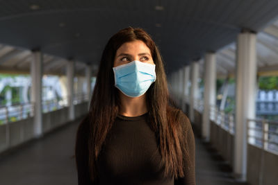 Portrait of young woman standing against blurred background