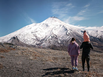 Rear view of man standing on mountain against sky