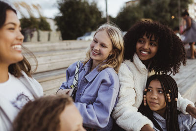 Happy female friends spending leisure time while sitting on pier