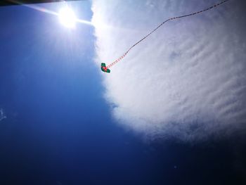 Low angle view of person paragliding against blue sky