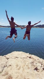 Rear view of shirtless man jumping in sea