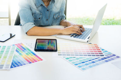 Midsection of man using laptop on table at home