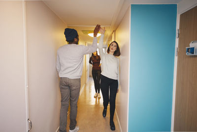 Rear view of man standing against wall at home