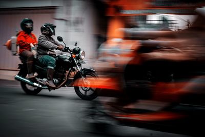 Blurred motion of people riding motorcycle on road