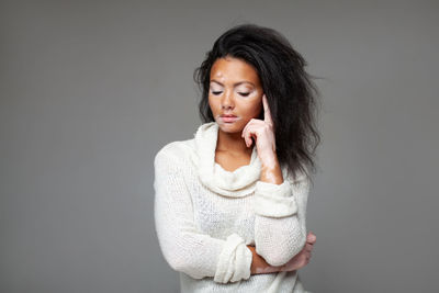 Portrait of young woman standing against black background