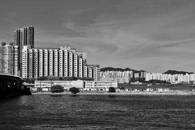 Buildings by sea against sky in city