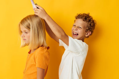 Boy combing against yellow background