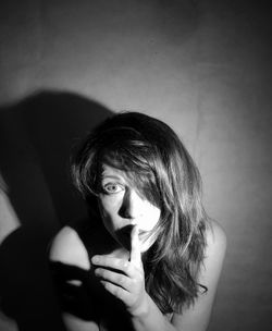 Portrait of young woman holding hair against wall