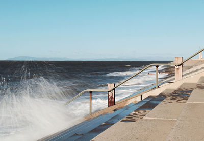 Scenic view of swimming pool by sea against clear sky