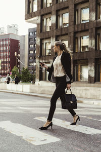 Female entrepreneur with smart phone crossing street