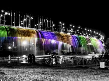 Multi colored light trails in city against sky at night