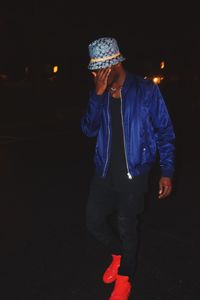 Man covering face while walking on street at night