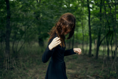 Full length of woman standing on field in forest