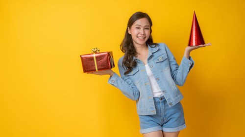 Portrait of a smiling young woman against yellow background