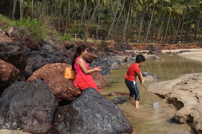 Rear view of people walking on rocks by stream