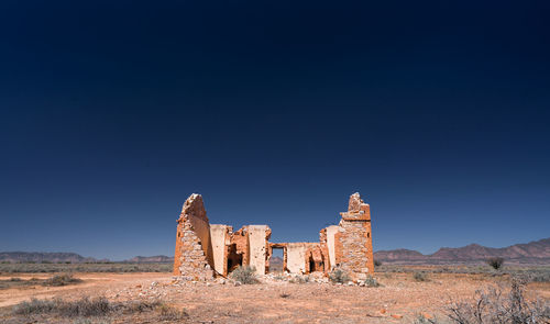 Old ruins of building on field against clear blue sky