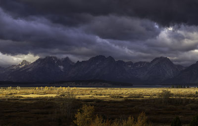 Scenic view of field and mountains against storm clouds