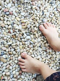 Close-up low section of boy standing on pebbles
