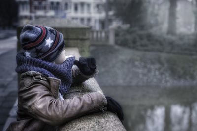 Close-up of boy by retaining wall during winter