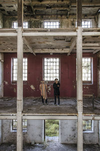Full length of friends standing in abandoned factory