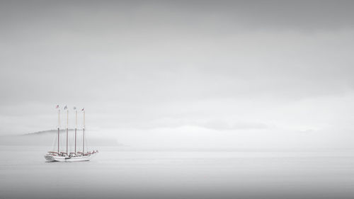 Sailboat sailing on sea against sky during foggy weather