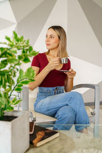 Young woman using mobile phone while sitting at home