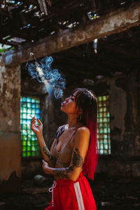 Side view of young woman smoking outdoors