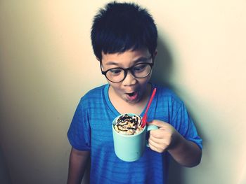 Portrait of boy holding ice cream against wall