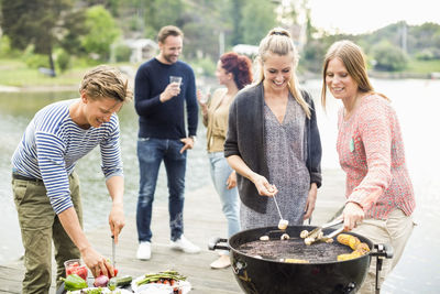 Group of friends enjoying barbecue party on pier