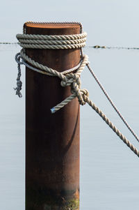 Rope tied on rusty metal post in river