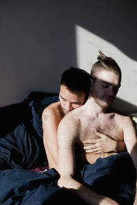 Young man sitting on bed at home
