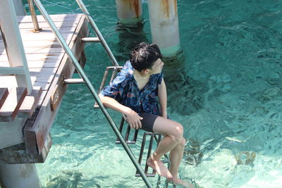 High angle view of man sitting on steps in swimming pool