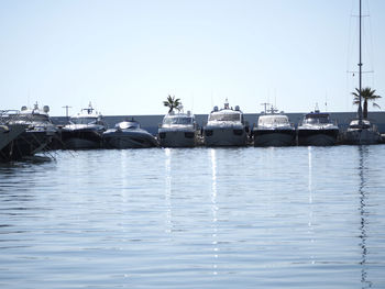 Boats in calm sea against clear sky