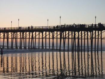 Silhouette pier over sea against clear sky during sunset