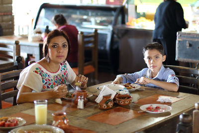 Portrait of mother and son having food in restaurant