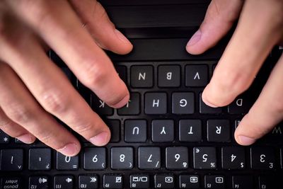 Cropped image of hands using laptop