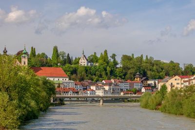 Houses by river and buildings against sky