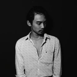 Portrait of young man against black background