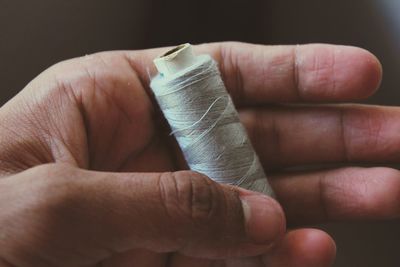 Close-up of hand holding thread spool