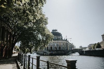 Bridge over river by buildings against clear sky