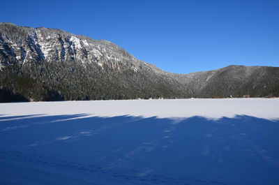 Scenic view of snowcapped mountains against clear blue sky