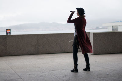 Full length rear view of woman standing against sky