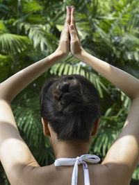Rear view of woman doing yoga against trees