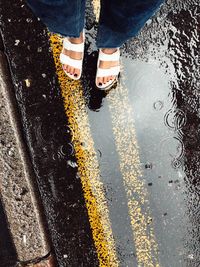 Low section of woman standing on road in rain
