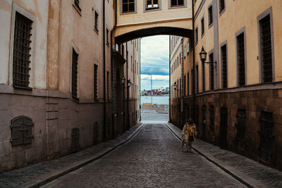 Rear view of man walking on street amidst buildings in city